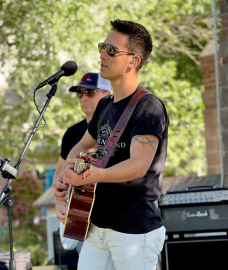 Musician with guitar singing in an outdoor setting
